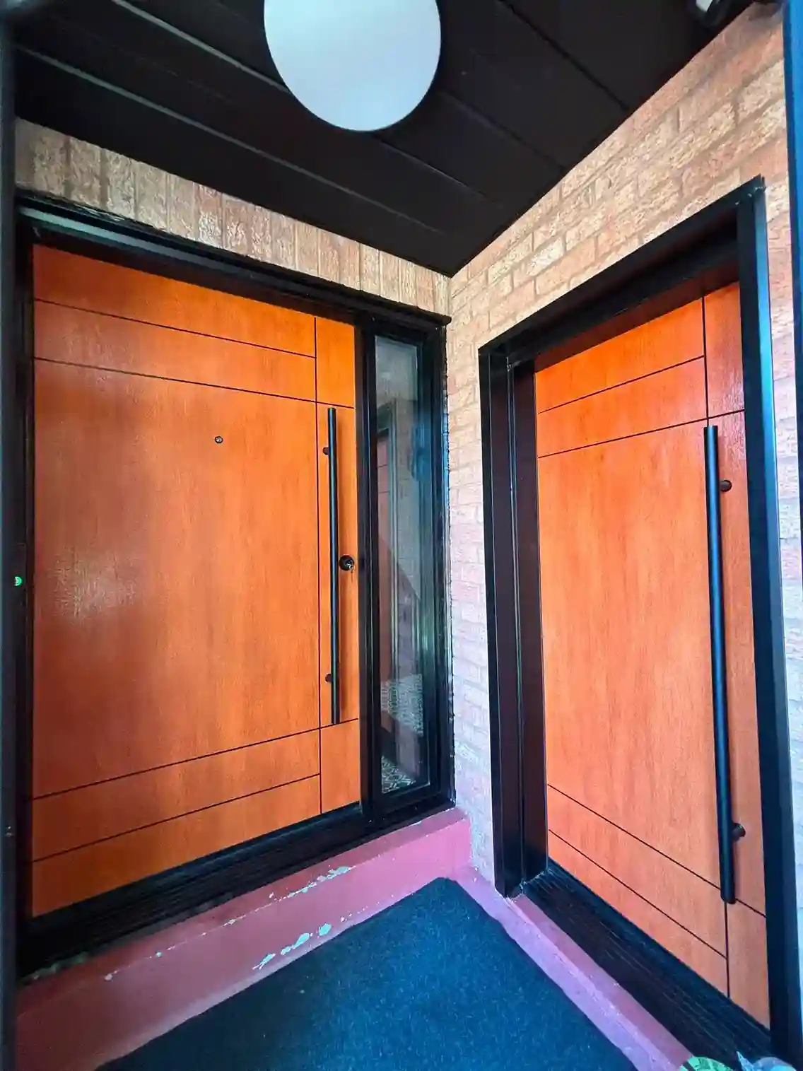 Modern Wood-Grain Orange Entry Door with Black Frame and Sidelight